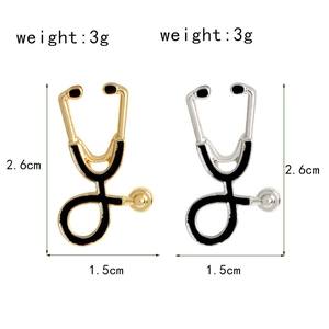 Detail view of gold and silver stethoscope brooches with 2.6cm x 1.5cm dimensions