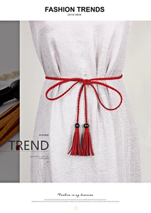 Detail of red braided waist rope with tassels and black beads on a light dress
