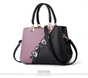 Detail view of purple leather handbag featuring elegant floral embroidery and gold hardware