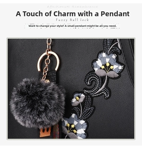 Detail of floral embroidery on black leather bag with a plush pompom keychain accessory