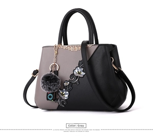 Detail of floral embroidery on a gray contrast stitching handbag with fur ball charm