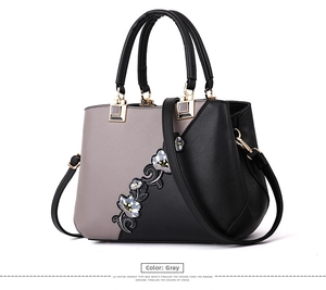 Close-up of grey leather bag with delicate floral embroidery and gold hardware detail