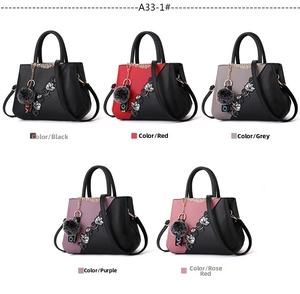 Detail of embroidered floral handbags in five colors with plush ball charms and straps
