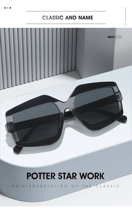 Close-up of geometric grey sunglasses on a white pedestal with elegant lighting