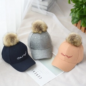 Flat lay of three baseball caps with fluffy pom poms and Black Royal embroidery details