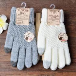 Detail of grey and white knitted touchscreen gloves with conductive fingertips and tags