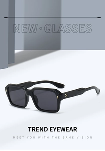 Detailed close-up of square black sunglasses with gold rivet accents and dark lenses