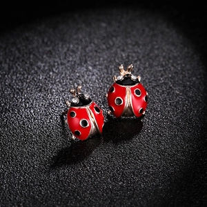 Vue macro de boucles d'oreilles coccinelle avec émail rouge et cristaux scintillants