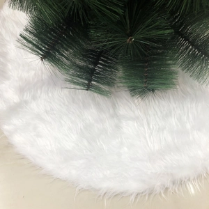 Close-up of soft white faux fur Christmas tree skirt with plush texture and pine needles