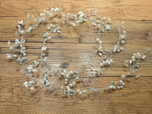 Close-up of handmade bridal headband with pearls and crystals on wooden background
