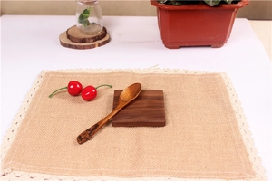 Close-up of walnut wood coaster with linen placemat and cherry blossom engraved wood spoon