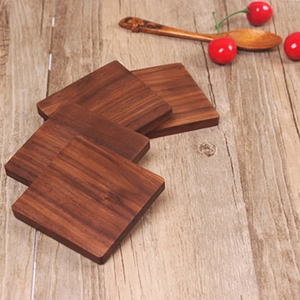 Top view of four square black walnut wood coasters with natural grain on a table