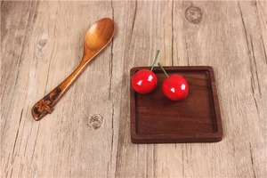 Detail of black walnut coaster with carved wooden spoon and decorative cherries