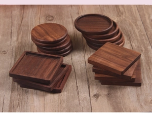 Detail of round and square black walnut wood coasters with raised edges on wooden surface