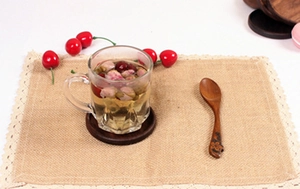Detail of dark walnut wooden coaster set with jute lace placemat and tea glass
