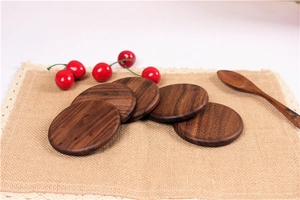 Stack of 5 round black walnut wood coasters on linen fabric with decorative wood spoon