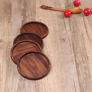 Detailed view of four round black walnut coasters with natural wood grain on a wooden table