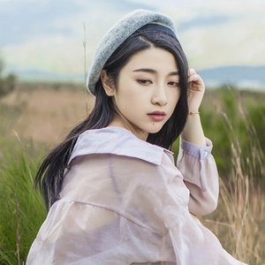 Detail of light gray straw beret with dark piping trim worn outdoors in soft sunlight