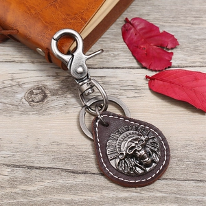 Vintage brown leather keychain with Indian skull badge on a wooden desk with maple leaves