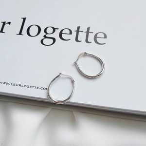 Close-up of solid 925 sterling silver U-shaped hoop earrings on a magazine background