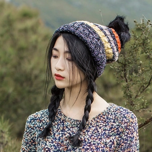 Detail of multi-color knitted straw hat featuring a black faux fur pompom for women