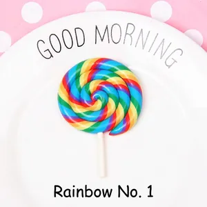 Rainbow spiral polymer clay lollipop accessory on a white plate with pink dot background
