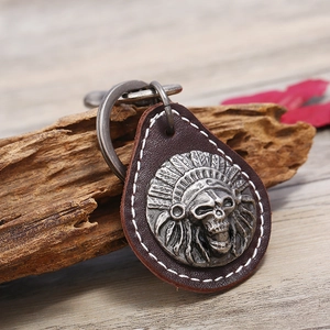 Vintage cowhide leather keychain with silver Indian skull relief on wood background