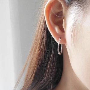 Close-up of 925 sterling silver horseshoe U-shaped earrings worn by a model in soft light