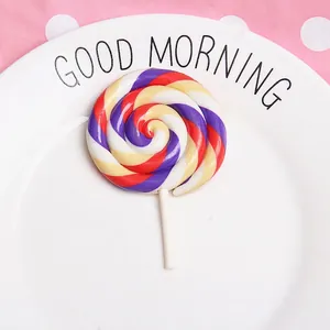 Detailed view of a purple-red spiral clay lollipop DIY accessory on a white ceramic plate