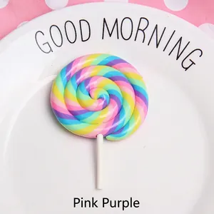 Close-up of a colorful spiral clay lollipop charm on a white ceramic plate