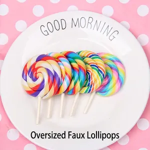 Five large colorful swirl fake lollipops arranged in a fan shape on a white plate
