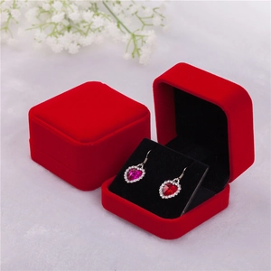 Red velvet jewelry box with heart shaped earrings set on a white soft surface