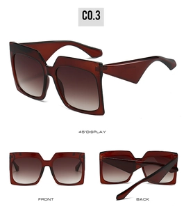 Detail view of square oversized sunglasses with amber red-brown frames and gradient lenses