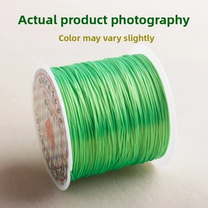 Macro shot of green elastic bead cord on white plastic spool for jewelry making