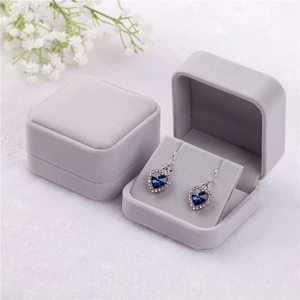 Gray velvet jewelry box featuring blue heart crystal earrings on an elegant background