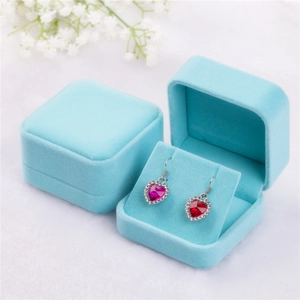 Detail view of heart-shaped red crystal earrings inside blue velvet jewelry boxes