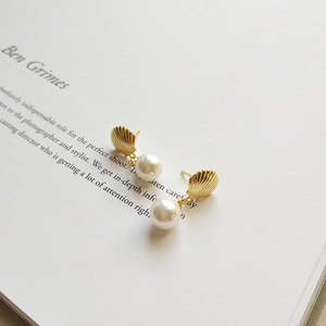 Elegant gold shell and pearl stud earrings in 925 sterling silver on a minimalist background