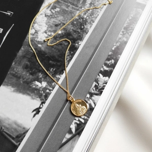 Macro view of gold-plated Maria coin pendant with detailed Mt. Carmel religious engraving