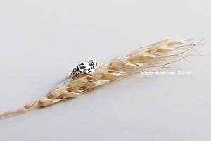 Artistic close-up of S925 sterling silver crying face ring on dried wheat stalk