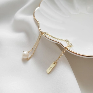 Macro detail of S925 sterling silver stamp and freshwater pearl on golden bracelet