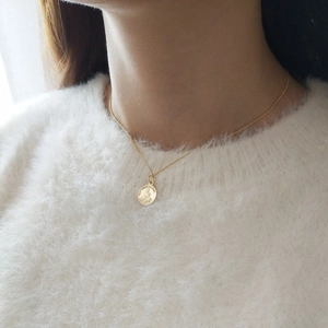 Macro view of gold 925 silver Virgin Mary medal necklace on white knit sweater