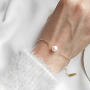 Detailed close-up of a minimalist S925 silver gold chain bracelet with a single freshwater pearl