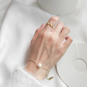 Close-up of a 925 sterling silver gold bracelet with a pearl and a cutout pattern ring