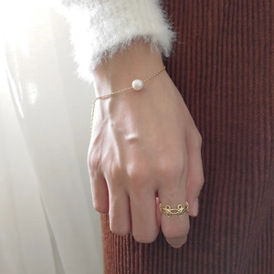 Detail of elegant S925 silver pearl bracelet and golden flower ring on model