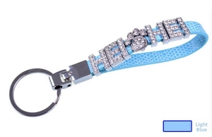 Macro shot of light blue leather keychain with rhinestone letters HE SHE and paw charm