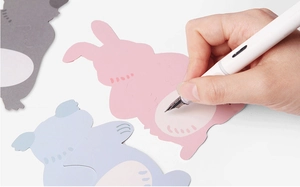 Close-up of hand writing with a white pen on cute pink animal-shaped candy card