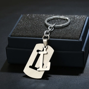 Close-up of brushed stainless steel letter L keychain with hollow design on black gift box