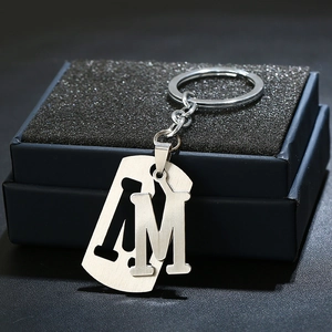Close-up of brushed stainless steel keychain with cutout letter M and rectangle pendant
