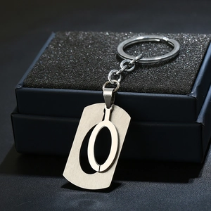 Macro detail of a brushed stainless steel letter O keychain in a premium black gift box