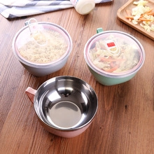 Close-up of stainless steel food bowls with lids in pink, green, and grey on wood table